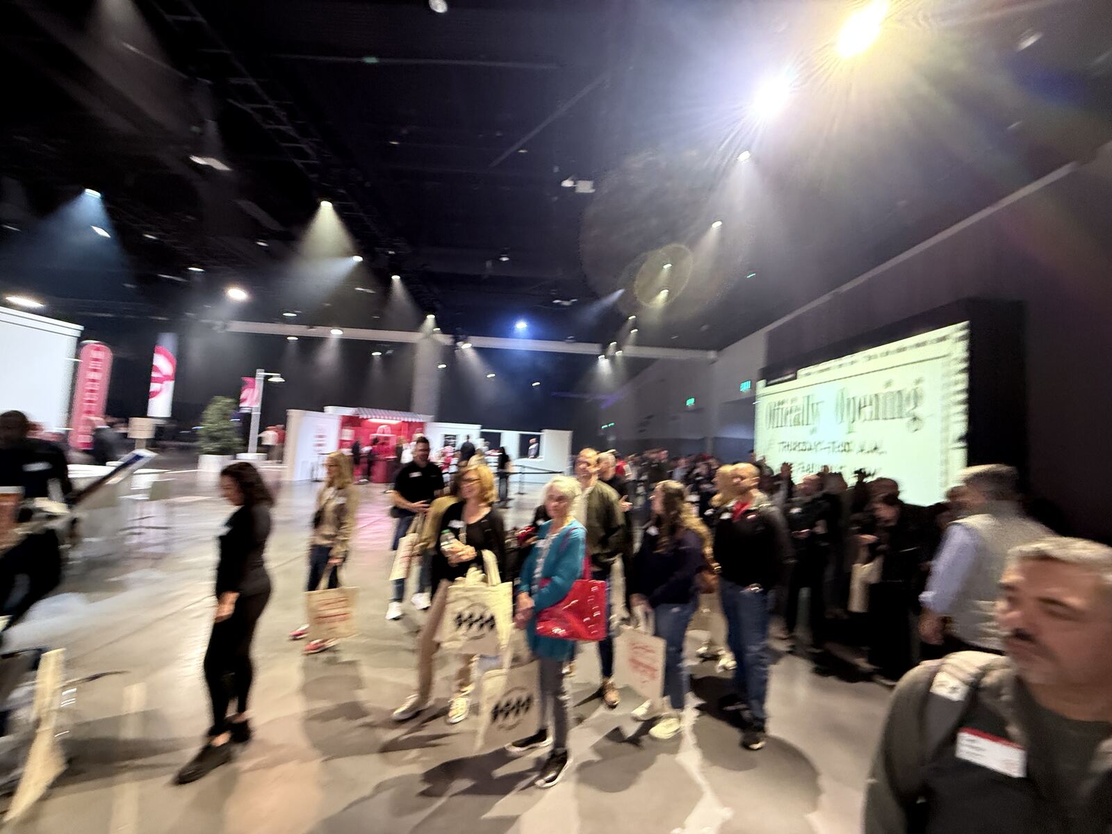 Wide shot of a large crowded indoor event floor with attendees and branding signage