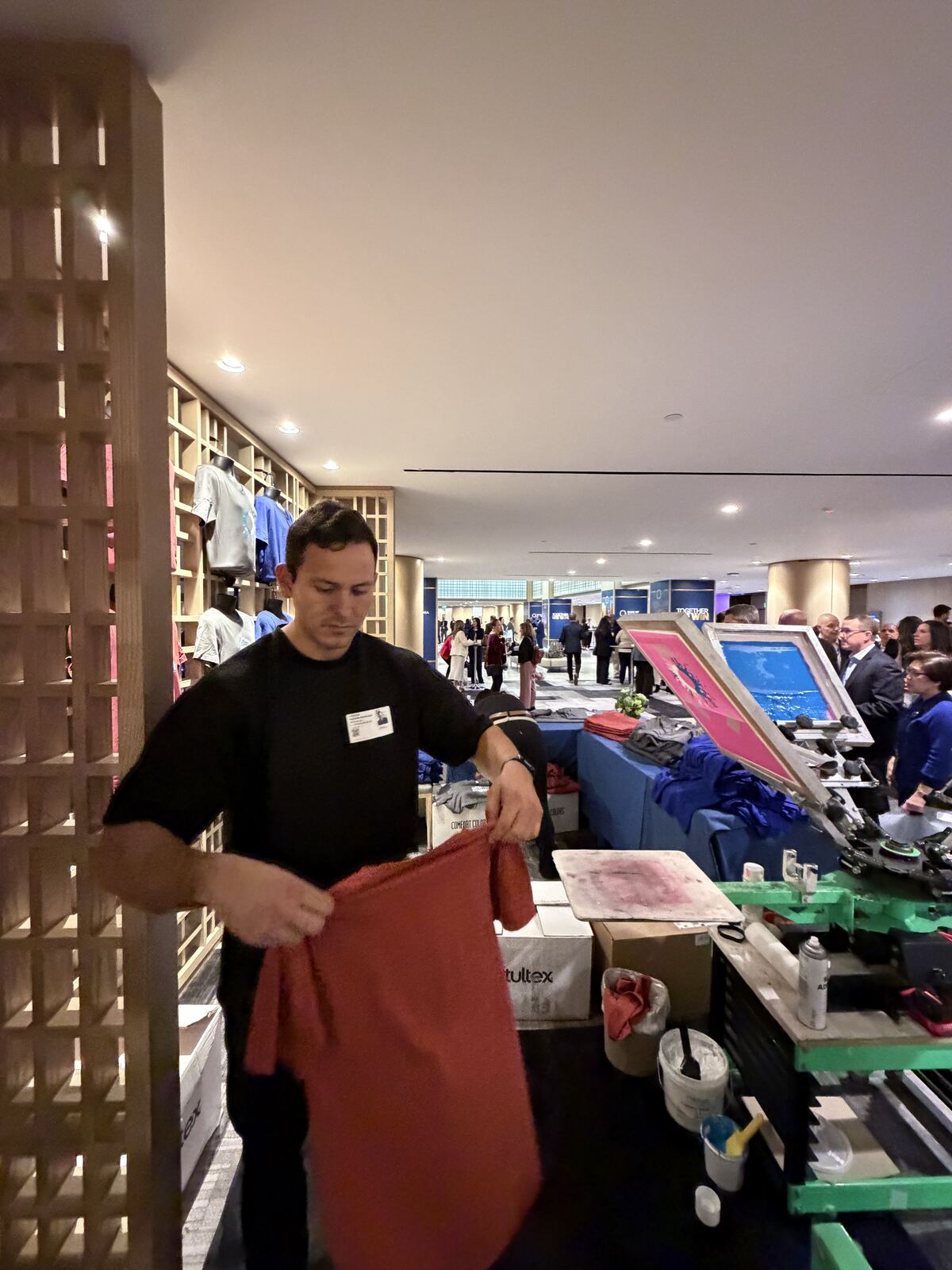 Overhead view of a screen printing demonstration with attendees watching at the booth